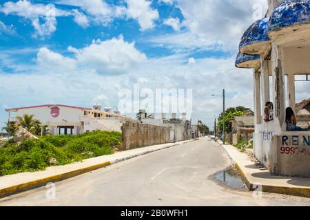 Rue du village de bord de mer sous le ciel bleu avec des nuages moelleux avec de l'eau debout, vélo dans la route et des femmes assis dans le pavillon au côté Yucatan M Banque D'Images