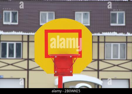 Support jaune vif avec anneau rouge pour une épée de basket-ball contre un mur d'un bâtiment résidentiel, terrain de sport extérieur. Stocker la photo au format horizontal avec un espace vide pour le texte et la conception. Banque D'Images