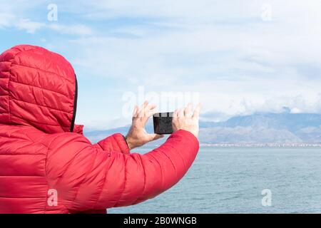 Homme méconnaissable prenant des photos avec un smartphone. Admirer la nature, la Wanderlust Banque D'Images