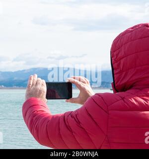 Homme méconnaissable prenant des photos avec un smartphone. Admirer la nature, la Wanderlust Banque D'Images