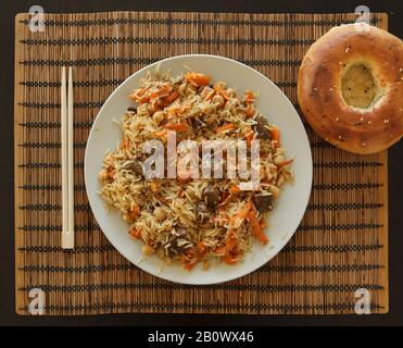 Le plov ouzbek est servi sur la plaque avec du pain plat ouzbek. Banque D'Images