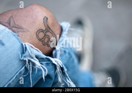 Homme avec un Jean déchiré et des tatouages sur son genou, gros plan, Banque D'Images