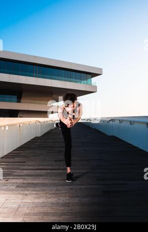 Jeune sportif exécutant des mouvements articulaires de yoga dans une zone urbaine de la ville. Banque D'Images