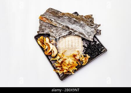 Ensemble d'ingrédients japonais traditionnels pour la cuisson du bouillon dashi de base. Algues kombu et wakame, katsuobushi et champignons secs. Isolé sur le backgro blanc Banque D'Images