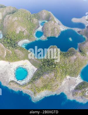 Les îles de calcaire accidentées s'élèvent à partir de l'assaisonnement serein de Raja Ampat, en Indonésie. Cette région tropicale est connue comme le cœur du Triangle de corail. Banque D'Images