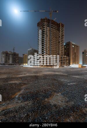 Sites de construction de bâtiments de grande taille dans Sports City la nuit, Dubaï, Emirats Arabes Unis, Banque D'Images