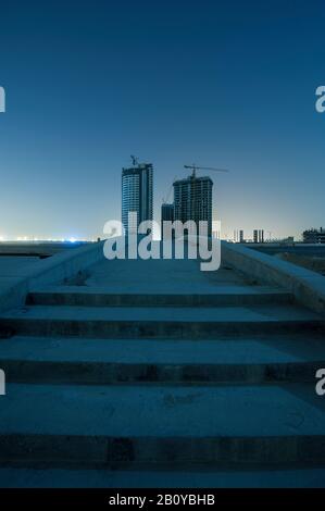 Sites de construction de bâtiments de grande taille dans Sports City la nuit, Dubaï, Emirats Arabes Unis, Banque D'Images