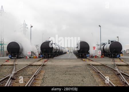 Wagons-citernes de chemin de fer utilisés pour le transport de produits pétroliers. Plusieurs cartes sont visibles. Le brouillard ou la fumée s'élève des voitures. Banque D'Images