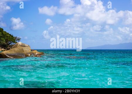 Nudey Beach, Fitzroy Island, les rochers traversent les eaux cristallines de la mer de corail avec la côte du Queensland Australie en arrière-plan. Banque D'Images