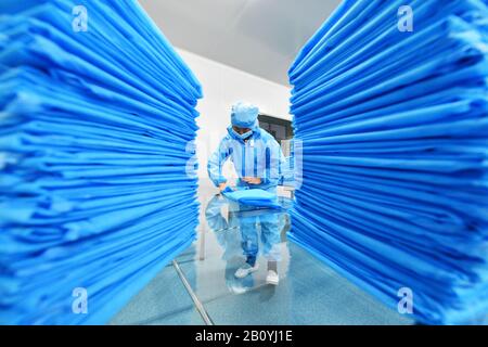 Xingyi. 21 février 2020. Un travailleur de la Junjiang Industrial Limited Company produit des blouses chirurgicales jetables dans le nouveau district de Yilong, dans la préfecture autonome de Bouyei-Miao de Qianxinan, dans le sud-ouest de la province de Guizhou, le 21 février 2020. Les entreprises d'approvisionnement médical du Nouveau district de Yilong ont produit des fournitures médicales à pleine capacité pour soutenir la lutte contre le nouveau coronavirus, ou COVID-19. Crédit: Yang Wenbin/Xinhua/Alay Live News Banque D'Images