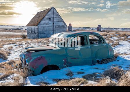 Voiture abandonnée et église sur une colline enneigée donnant sur des élévateurs de grain jumeaux à Neidpath, SK Banque D'Images