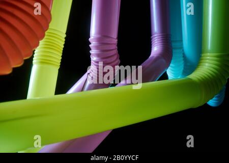 Arrière-plan des tubes à cocktail en plastique multicolores sur fond sombre Banque D'Images