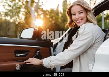 Image de la jeune femme caucasienne de belle femme d'affaires assise dans une voiture de luxe à l'extérieur Banque D'Images