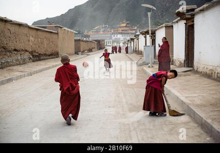 Les petits moines jouent au football dans les rues du village du monastère de Labrang, dans la province de Gansu, en Chine Banque D'Images