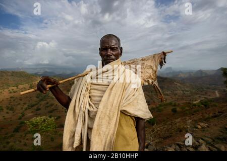 Un homme tigroyan tient un bâton avec un morceau séché de peau de chèvre, les montagnes Simien, Ethiopie Banque D'Images