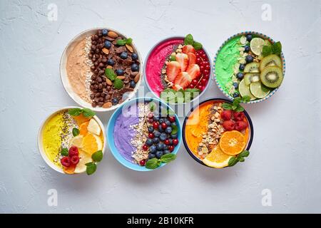 Divers smoothies ou yaourts frais dans des bols. Avec fraises, kiwi, chia, mûres Banque D'Images