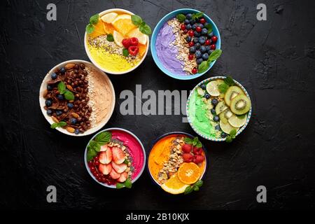 Divers smoothies ou yaourts frais dans des bols. Avec fraises, kiwi, chia, mûres Banque D'Images