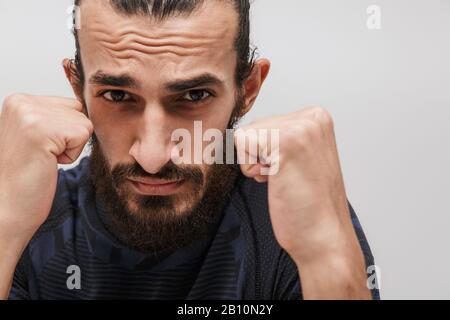 Image d'un sportif de brunette barbu portant un tracksuit de boxe à l'appareil photo isolé sur fond blanc Banque D'Images