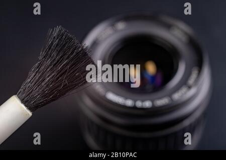 Nettoyage de la lentille photographique. Élimination de la poussière et de la saleté des accessoires photo. Fond sombre. Banque D'Images