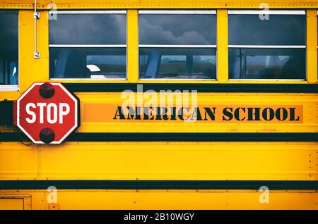 Bus scolaire américain jaune classique transportant des enfants à l'école. Retour au concept scolaire. Panneau d'arrêt rouge côté bus scolaire. Banque D'Images