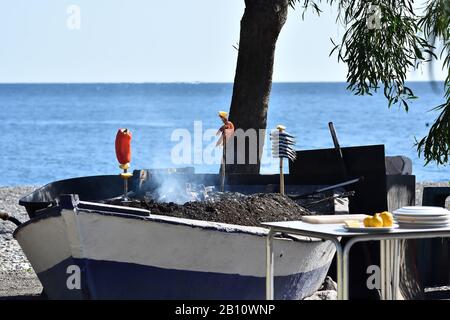 Cuisine typique de la côte andalouse : sardines et crevettes rôtissant par un feu de charbon dans un bateau Banque D'Images