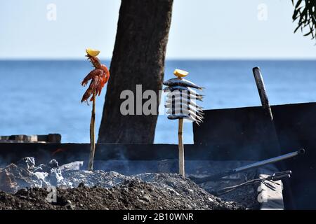 Cuisine typique de la côte andalouse : sardines et crevettes rôtissant par un feu de charbon dans un bateau Banque D'Images