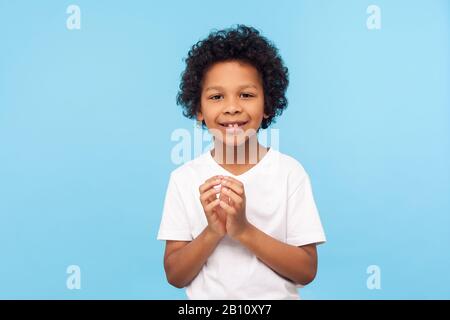 Portrait d'un petit garçon drôle et sournois en T-shirt pensant à une idée corsée et souriant à l'appareil photo, enfant désobéissant ayant des plans difficiles à l'esprit Banque D'Images