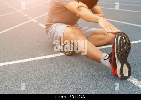 Jeune homme coureur étirant les jambes avant la course - concept d'entraînement Banque D'Images
