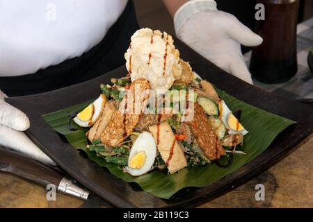 Cours de cuisine, plat prêt servi sur une plaque dans les mains de la cuisinière. Indonésie Bali nourriture. Banque D'Images