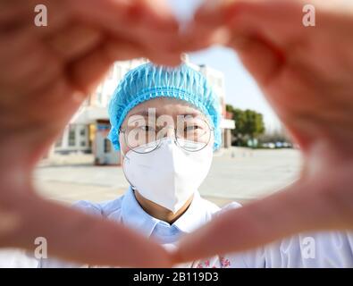 Une travailleuse médicale chinoise masquée fait un cœur avec ses mains lorsqu'elle retourne avec d'autres collègues à leurs propres postes après un isolement de 14 jours an Banque D'Images