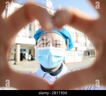 Une travailleuse médicale chinoise masquée fait un cœur avec ses mains lorsqu'elle retourne avec d'autres collègues à leurs propres postes après un isolement de 14 jours an Banque D'Images