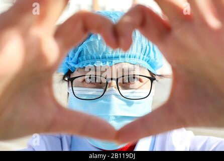 Une travailleuse médicale chinoise masquée fait un cœur avec ses mains lorsqu'elle retourne avec d'autres collègues à leurs propres postes après un isolement de 14 jours an Banque D'Images