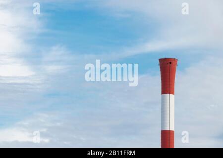 Gros plan sur une cheminée sans fumée enfumé en bandes rouges et blanches lors d'une journée ensoleillée contre le ciel bleu Banque D'Images