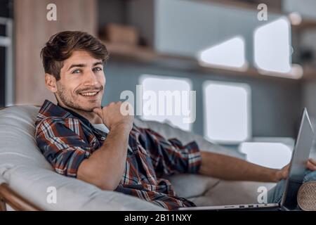 Close up. rêver jeune homme assis en face d'un ordinateur portable ouvert Banque D'Images