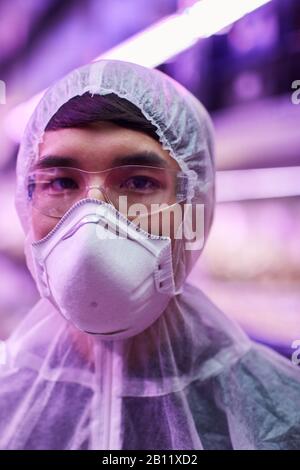 Portrait de l'homme asiatique portant des vêtements de protection pendant son travail dans un laboratoire chimique Banque D'Images