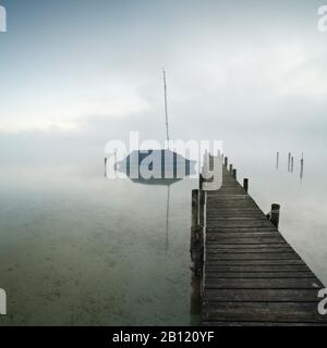 Matin d'automne sur le lac Chiemsee, jetée et voilier dans le brouillard, Bavière, Allemagne Banque D'Images