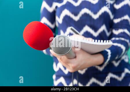 Journaliste ou journaliste féminin à la conférence de presse, tenant des notes de microphone et d'écriture Banque D'Images