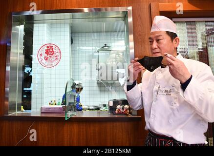 (200222) -- TIANJIN, 22 février 2020 (Xinhua) -- Yang Ming prend une pause à l'extérieur de la cuisine de son restaurant à Tianjin, dans le nord de la Chine, 22 février 2020. Chaque jour, Yang Ming, le propriétaire de 55 ans du restaurant « Caigentan », offre plus de 20 prises de vue gratuites aux membres du personnel qui luttent contre le nouvel épisode de coronavirus dans les communautés voisines. Cette idée est arrivée dans l'esprit de Yang lorsqu'il a entendu les travailleurs de la communauté avoir des ennuis avec les repas car la plupart des restaurants avaient été fermés. Yang travaille de 7 h à 19 h tous les jours pour préparer et livrer les plats à emporter pour le déjeuner et le dîner à l'heure. 'T Banque D'Images