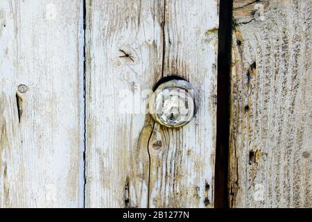 Ancienne serrure de cylindre Yale dans une porte en bois peinte et dépeinte, réutilisée comme porte de hangar de poulet. Banque D'Images