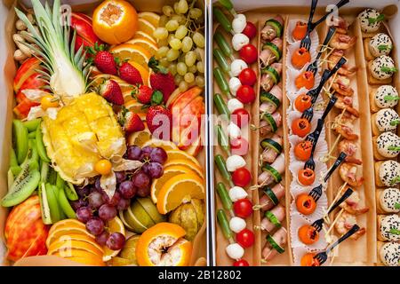 Différents types de canapés avec du poisson, des légumes frais et du fromage dans une boîte spéciale pour une commande. Beaucoup de fruits tranchés tels qu'ananas, oranges, Banque D'Images