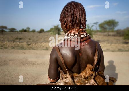 Femme Hamar avec des cheveux ocre et des bijoux près de sa maison dans la vallée de l'Omo, en Ethiopie Banque D'Images