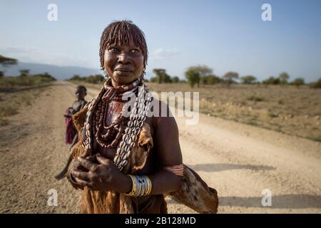 Femme Hamar avec des cheveux ocre et des bijoux près de sa maison dans la vallée de l'Omo, en Ethiopie Banque D'Images