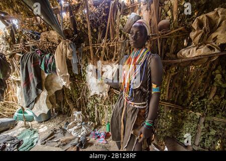 Fille de tribu Arbore dans la vallée Omo à l'intérieur de sa hutte faite de branches et de feuilles, Ethiopie Banque D'Images