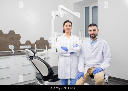 Deux jeunes dentistes professionnels en gants et en blanchons vous regardant Banque D'Images