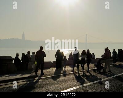 La vue de la place Comercio sur la rivière, le pont du 25 avril et la statue de Cristo Rei est plus belle lorsque le soleil descend dans la brume. Banque D'Images