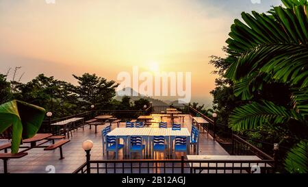 Point de vue à angle élevé pour regarder le magnifique paysage naturel ciel coloré pendant le coucher du soleil. Table et chaises sur la terrasse pour dîner de la res Banque D'Images