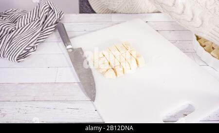 Étape par étape. Coupe de fudge de canne à sucre fait maison sur un tableau de découpe blanc. Banque D'Images