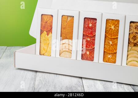 Des boîtes de chips de fruits se trouvent sur un fond en bois blanc, arrière-plan vert clair Banque D'Images