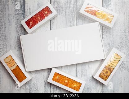 Des boîtes de chips de fruits se trouvent sur un fond en bois blanc Banque D'Images