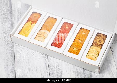 Des boîtes de chips de fruits se trouvent sur un fond en bois blanc Banque D'Images